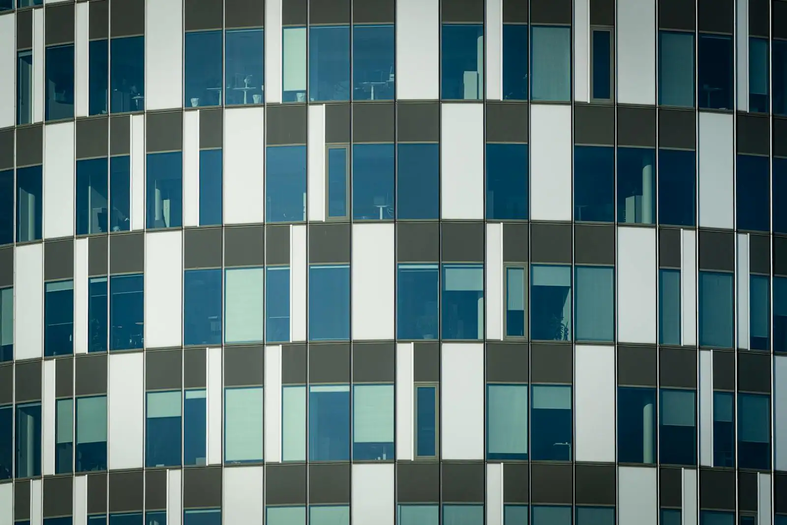 Façade vitrée d'un immeuble moderne reflétant le ciel, illustrant les matériaux de construction