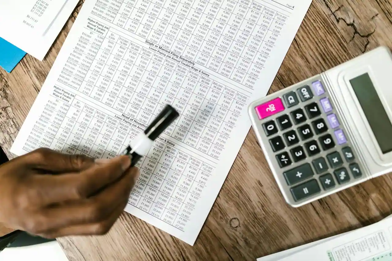 Calculatrice posée sur des documents fiscaux et des formulaires, illustration du calcul de l'impôt sur le revenu