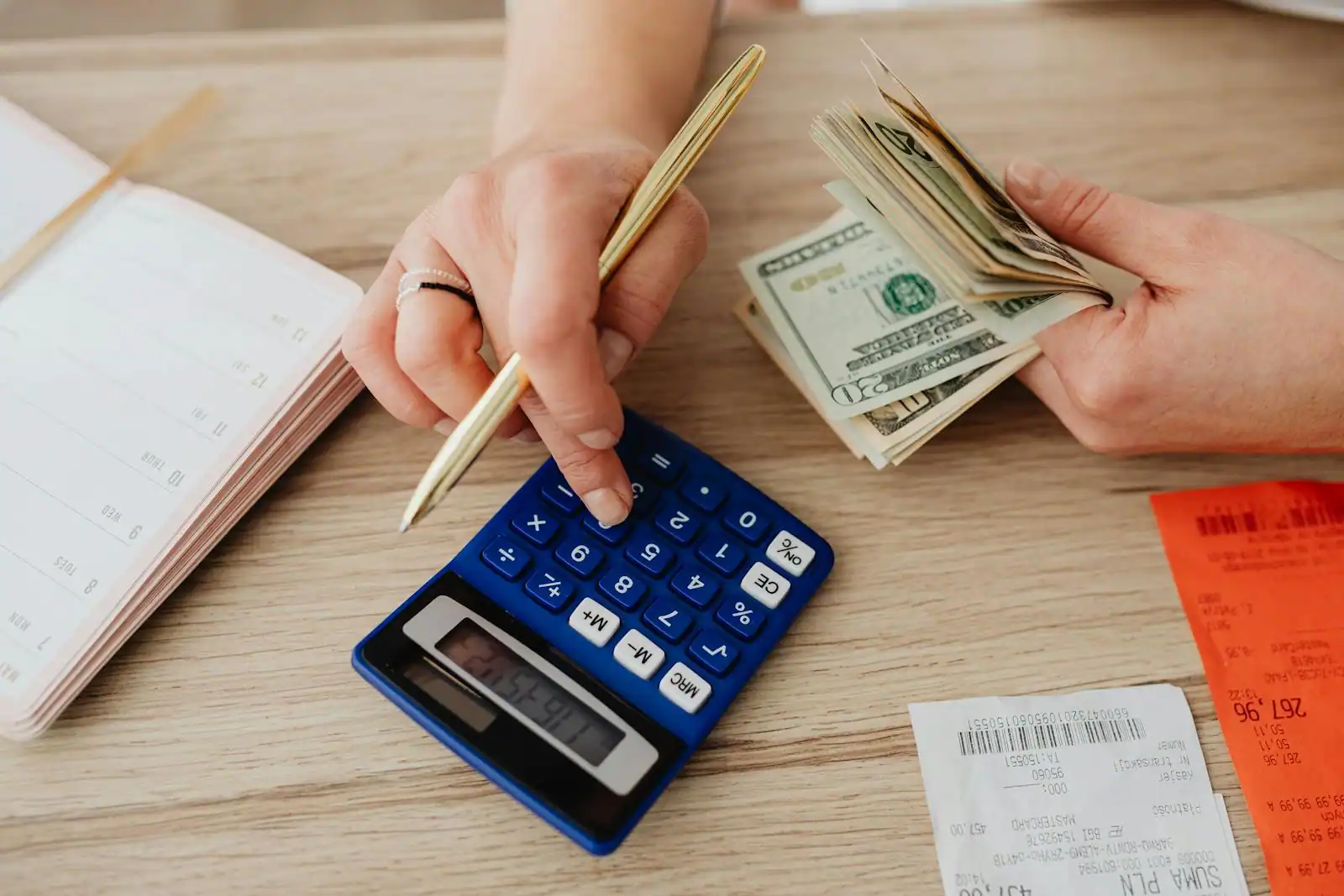 Personne calculant son épargne avec un carnet et une calculatrice sur une table