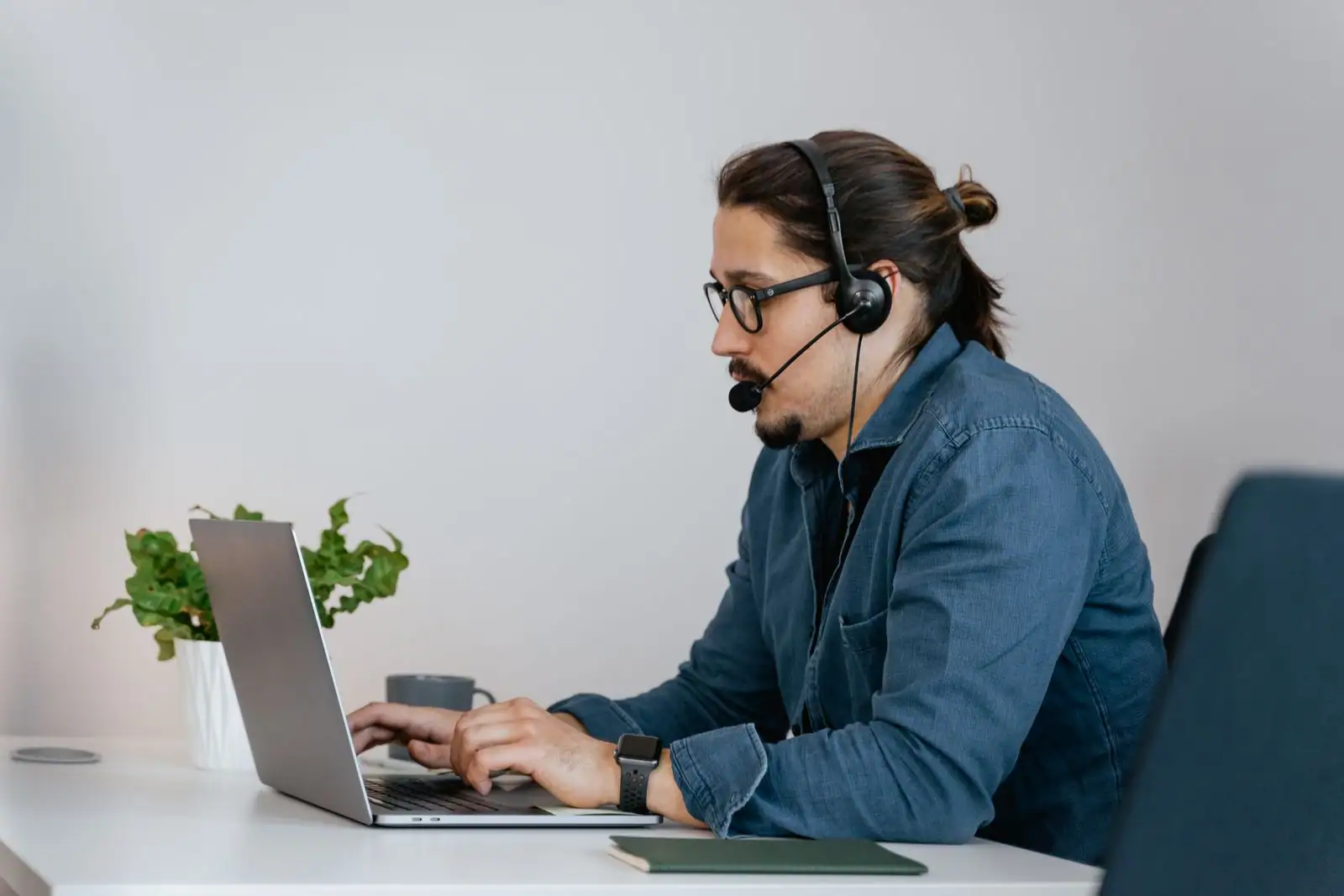 Agent de support client portant un casque-micro et travaillant sur un ordinateur portable