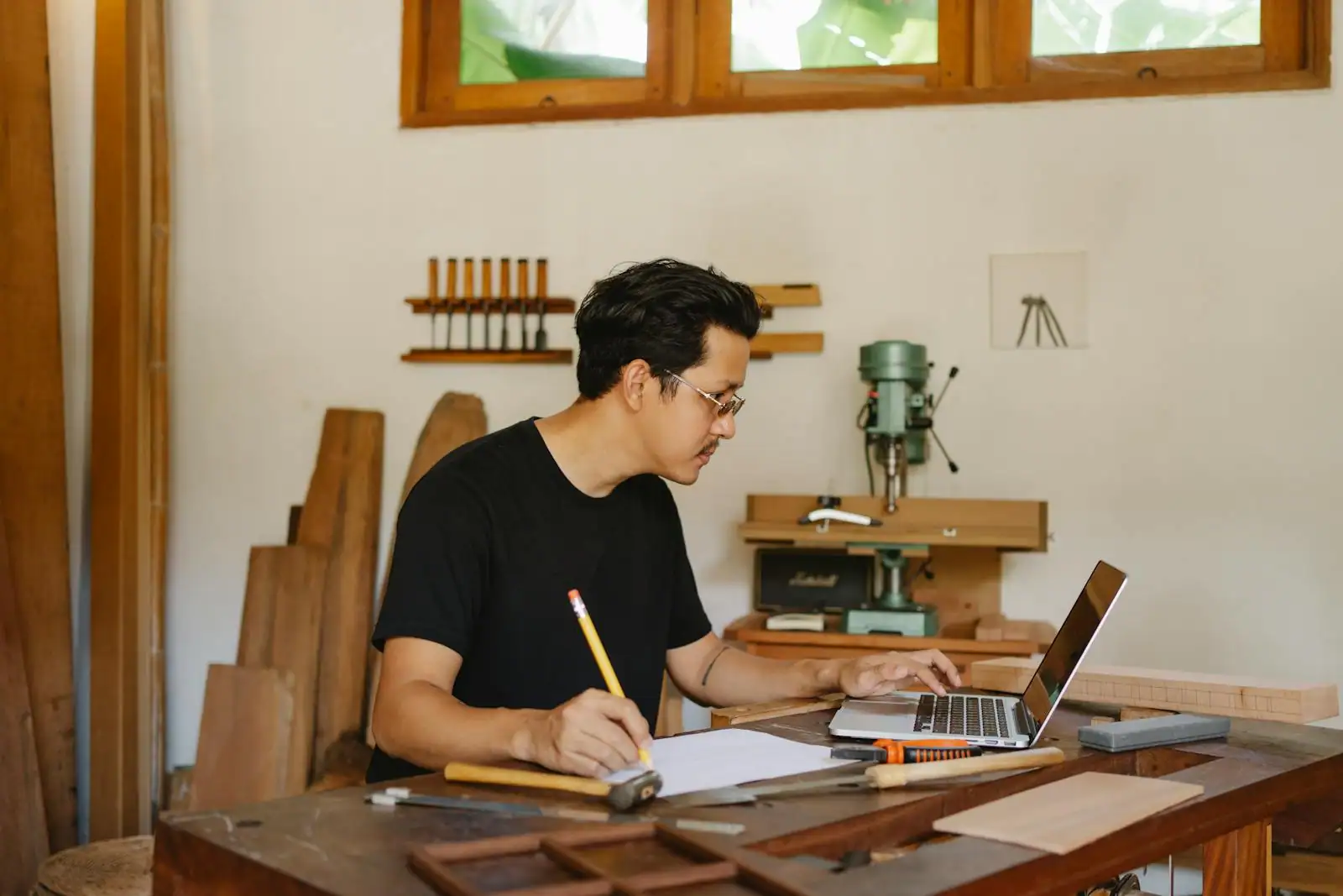 Jeune entrepreneur indépendant travaillant sur son ordinateur portable dans un petit atelier lumineux.