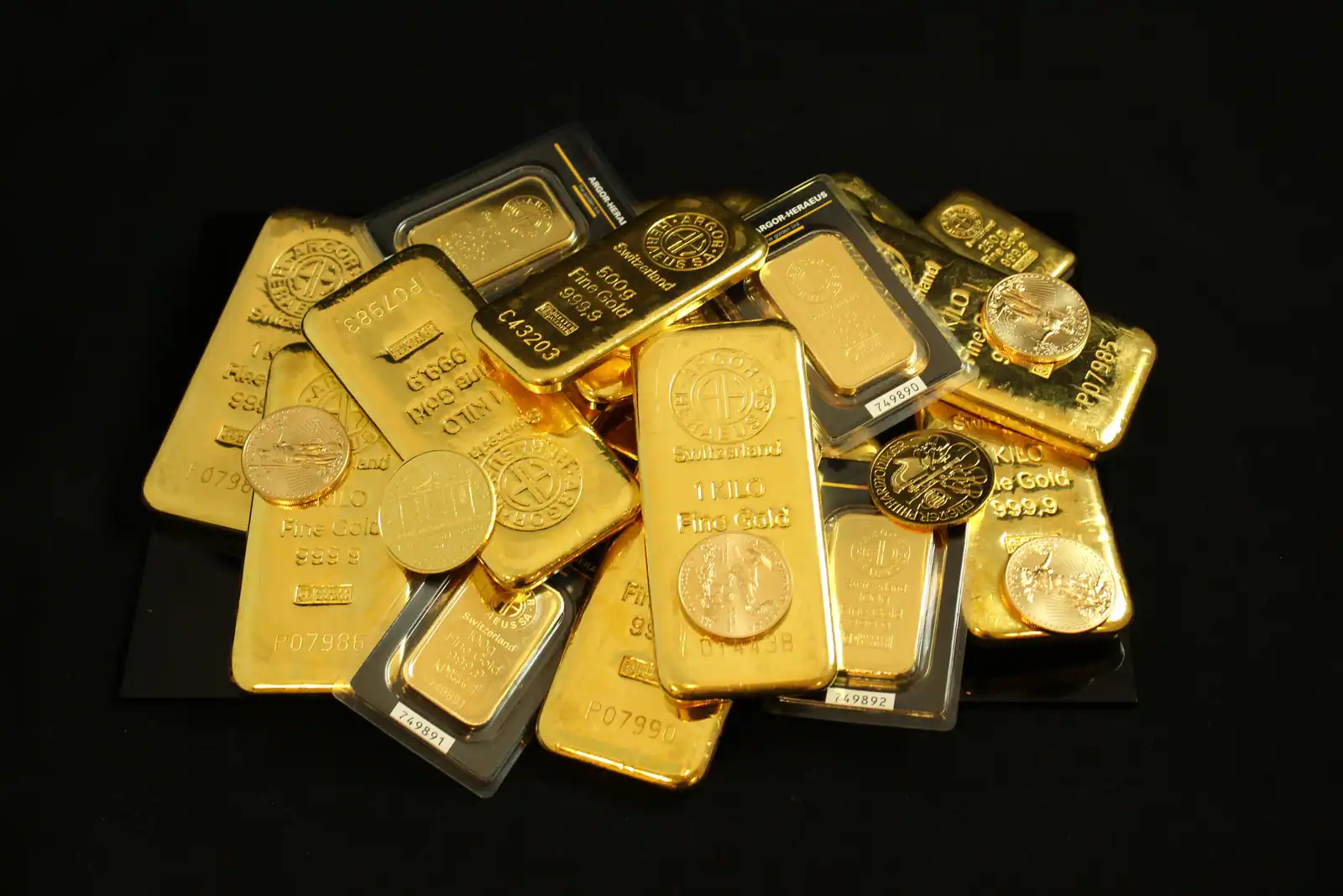 Lingots et pièces d'or empilés sur une surface sombre, illustrant l'investissement dans l'or
