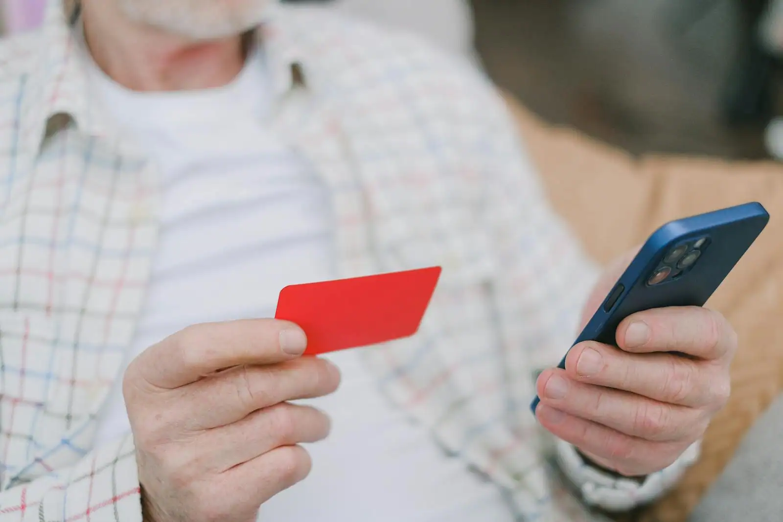Personne tenant une carte rouge dans une main et un smartphone dans l'autre