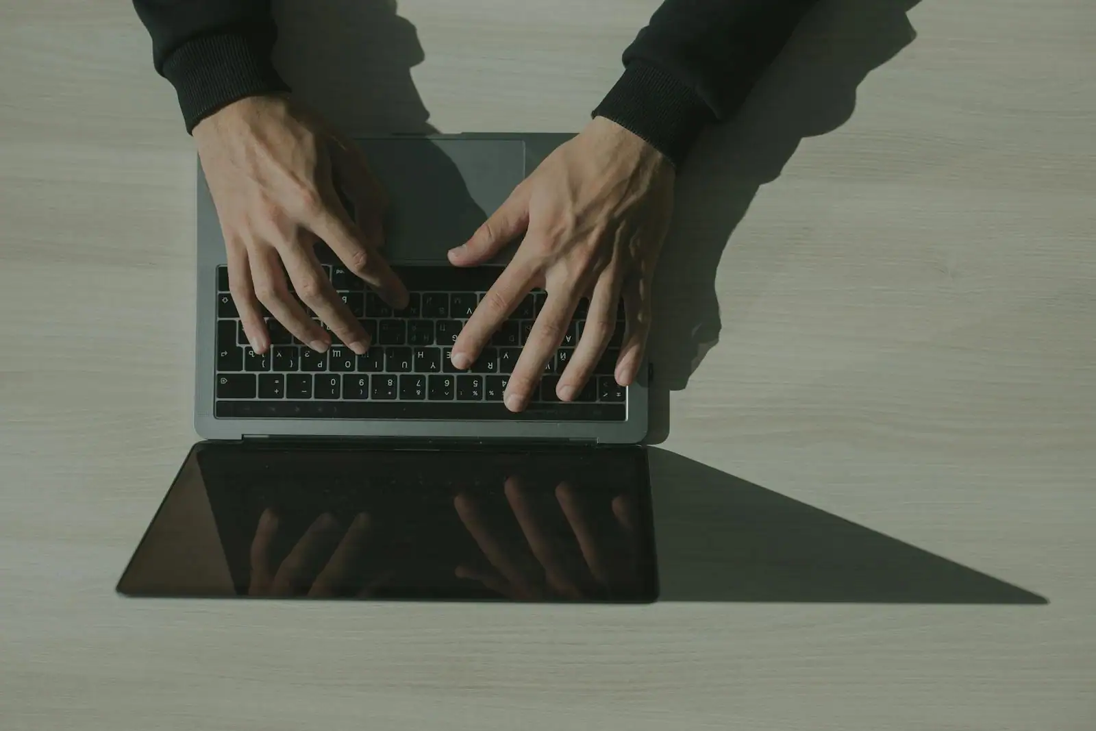 Vue de dessus de deux mains en train de taper sur le clavier d'un ordinateur portable.