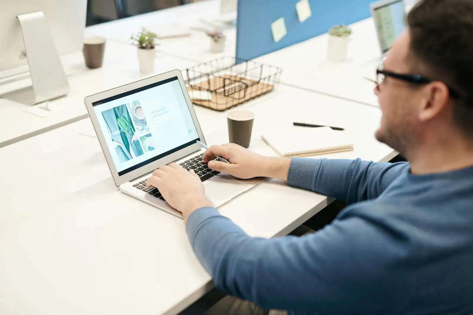 Personne utilisant un ordinateur portable à un bureau lumineux, avec une tasse de café et un carnet posés à côté