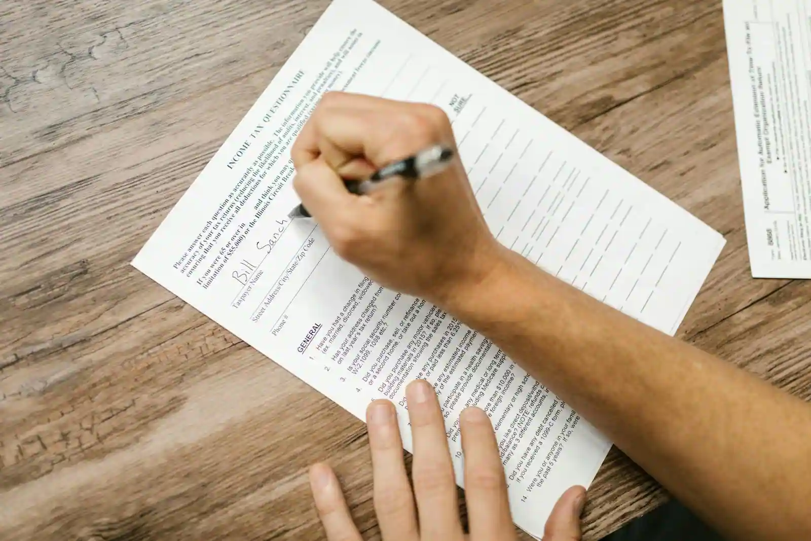 Mains remplissant un formulaire de déclaration de revenus au stylo