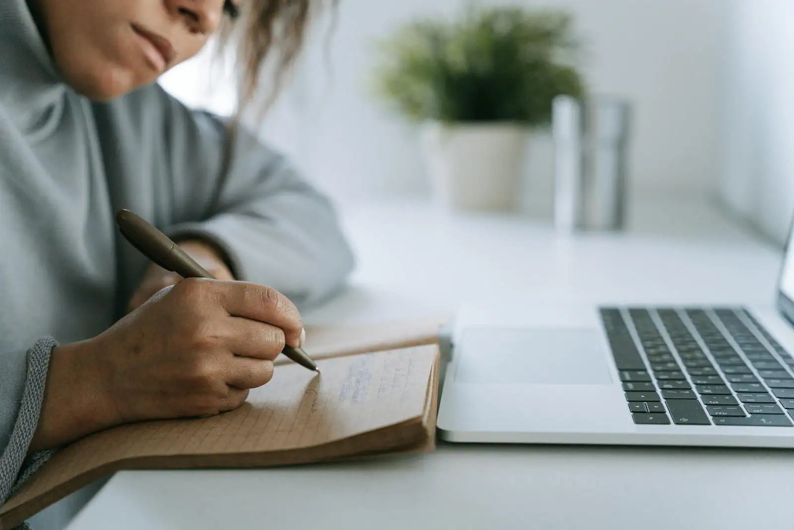 Personne réfléchissant à sa reconversion devant un carnet et un ordinateur portable, ambiance de changement professionnel.