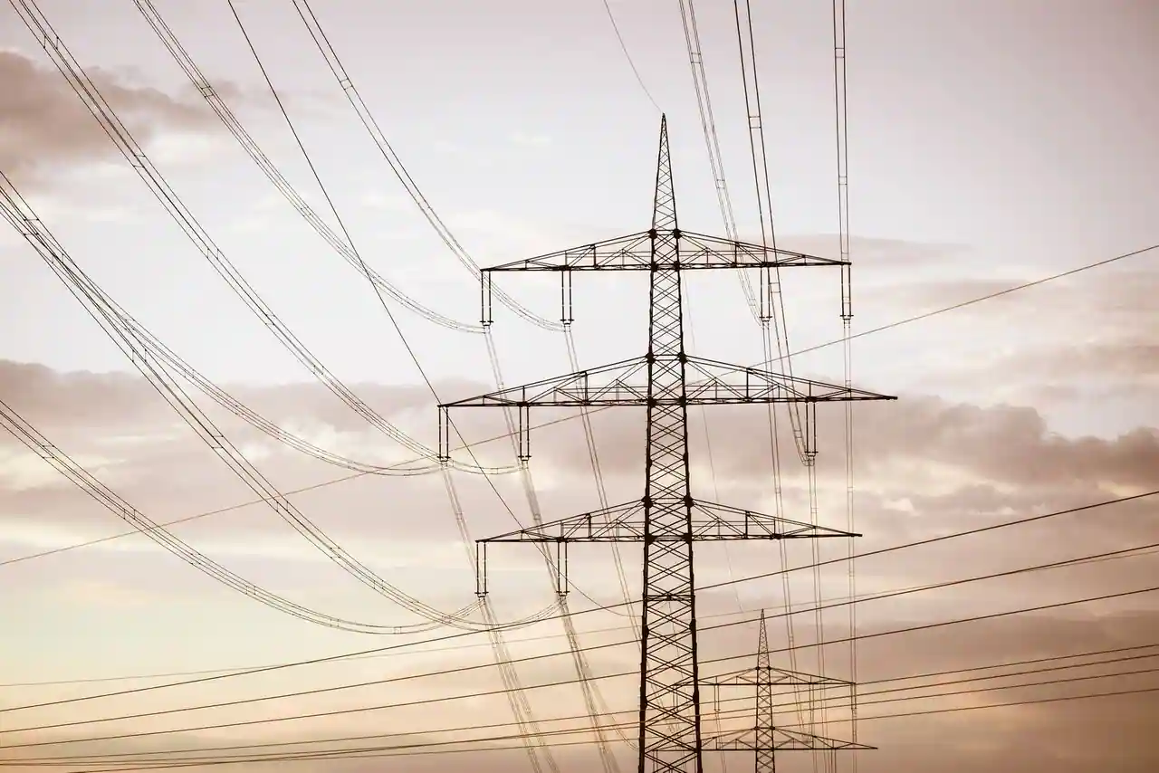 Lignes à haute tension et pylônes électriques au coucher du soleil, illustrant le secteur de l'énergie.