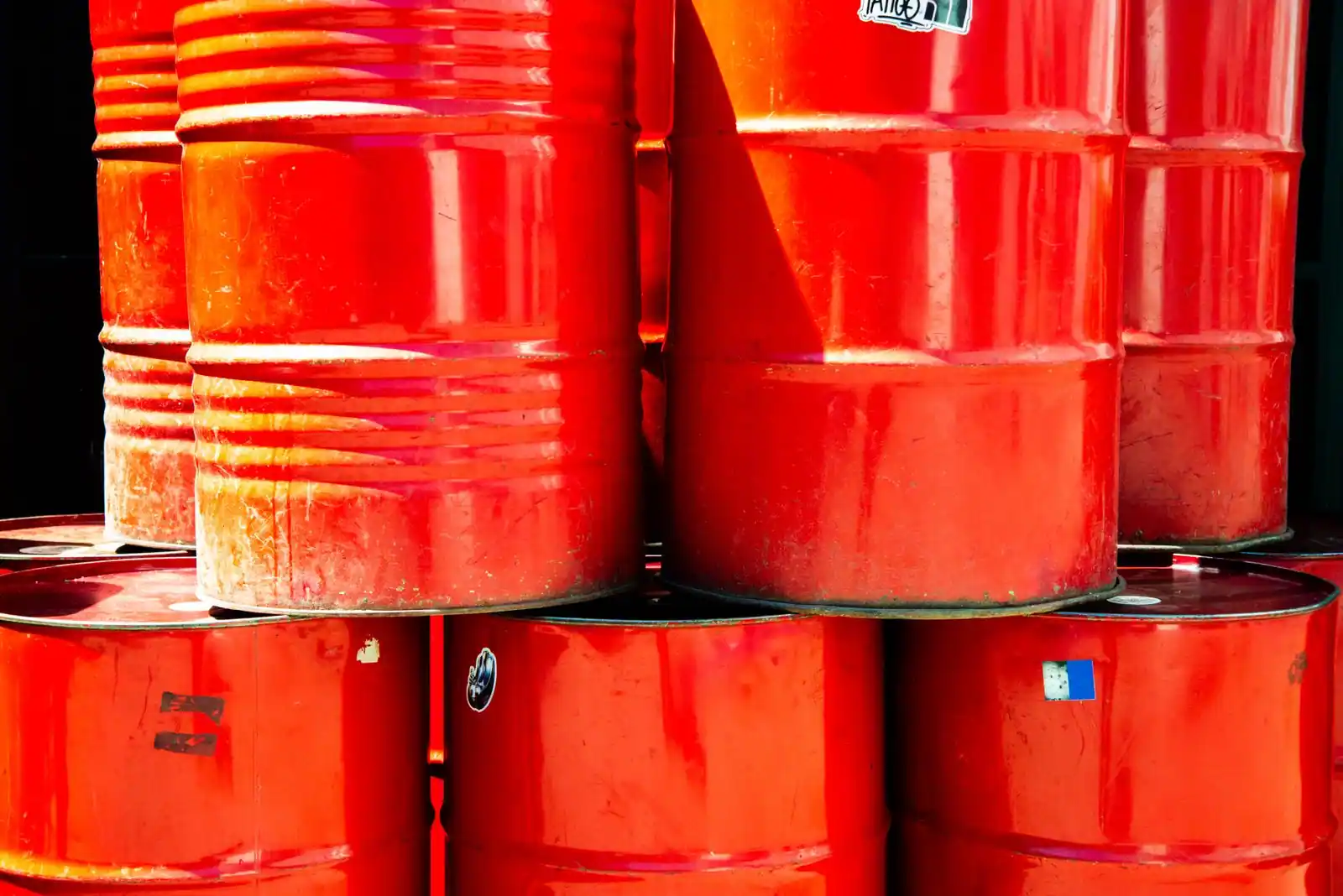 Fûts industriels rouges empilés, une image évoquant le marché du pétrole.