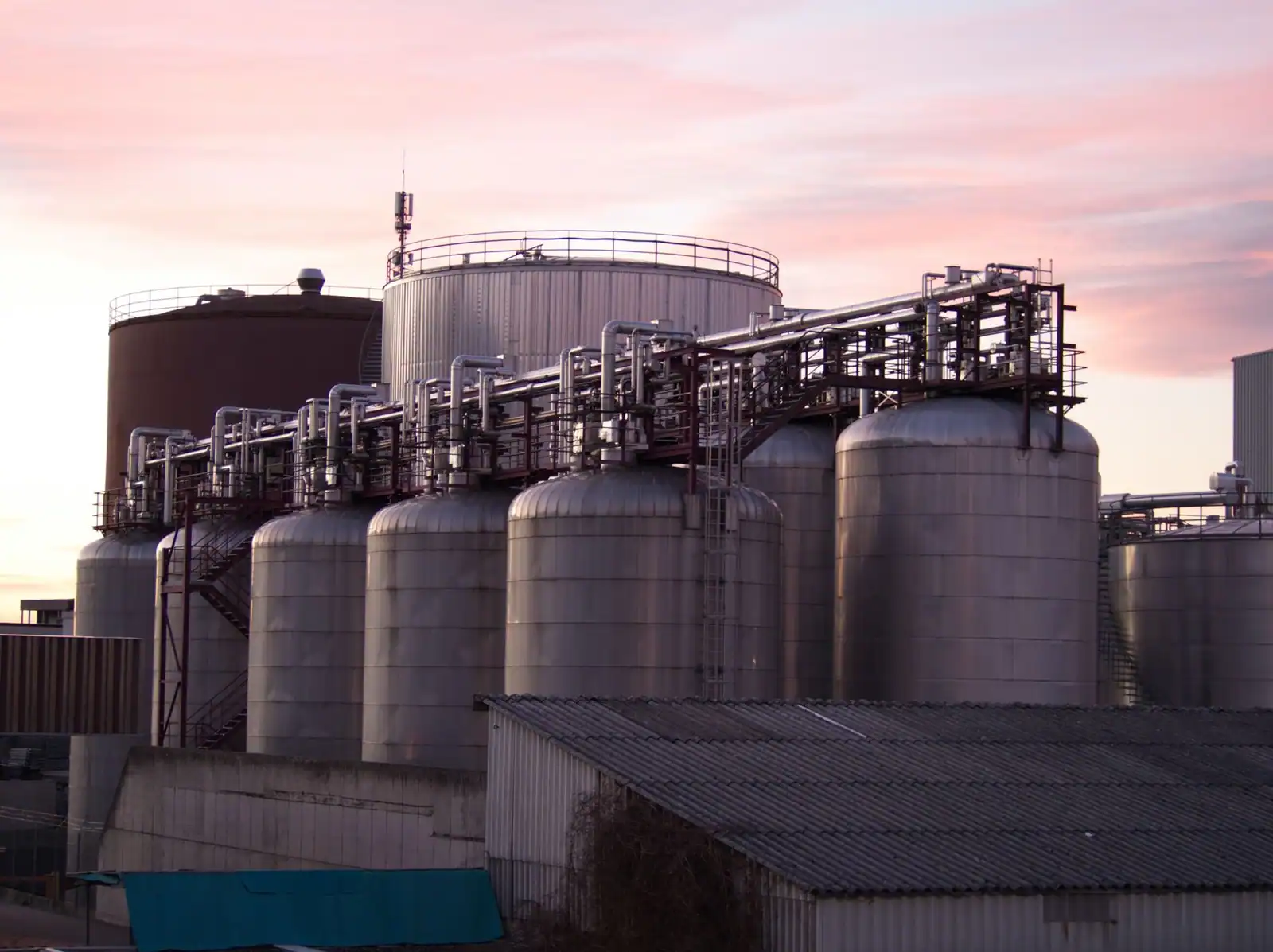 Cuves de stockage d'un site pétrolier et gazier au crépuscule, évoquant le secteur d'activité de TotalEnergies.