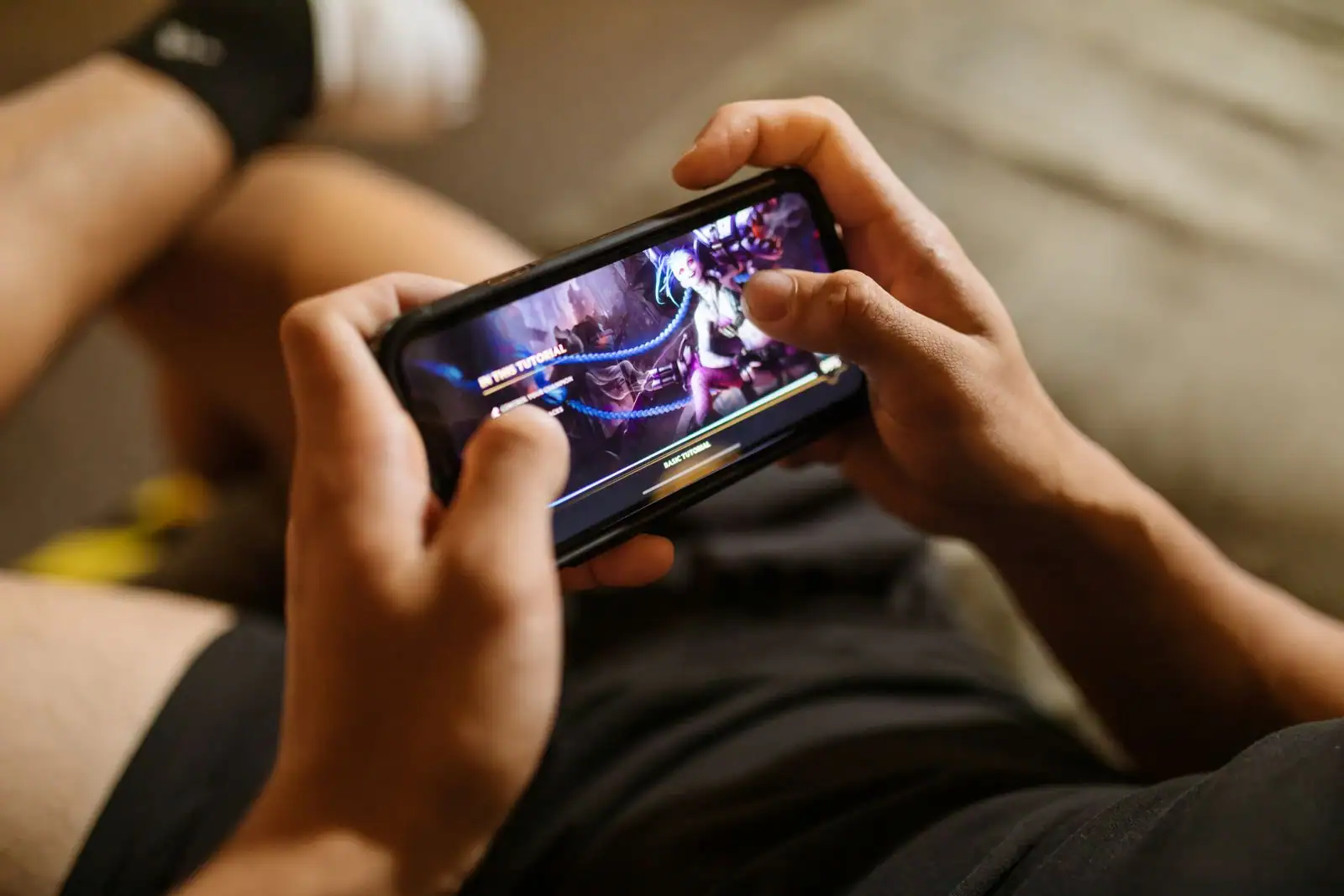 Jeune personne concentrée jouant à un jeu mobile sur son smartphone tenu à deux mains