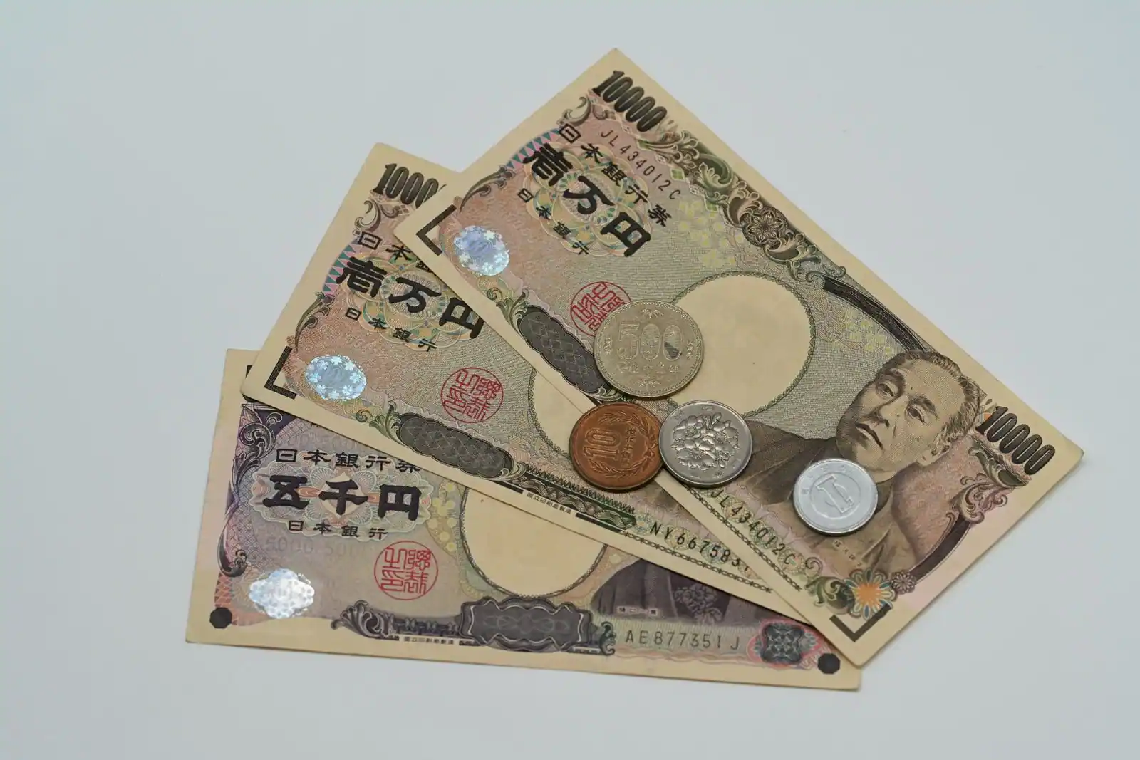 Billets et pièces en yens japonais posés sur une surface claire.