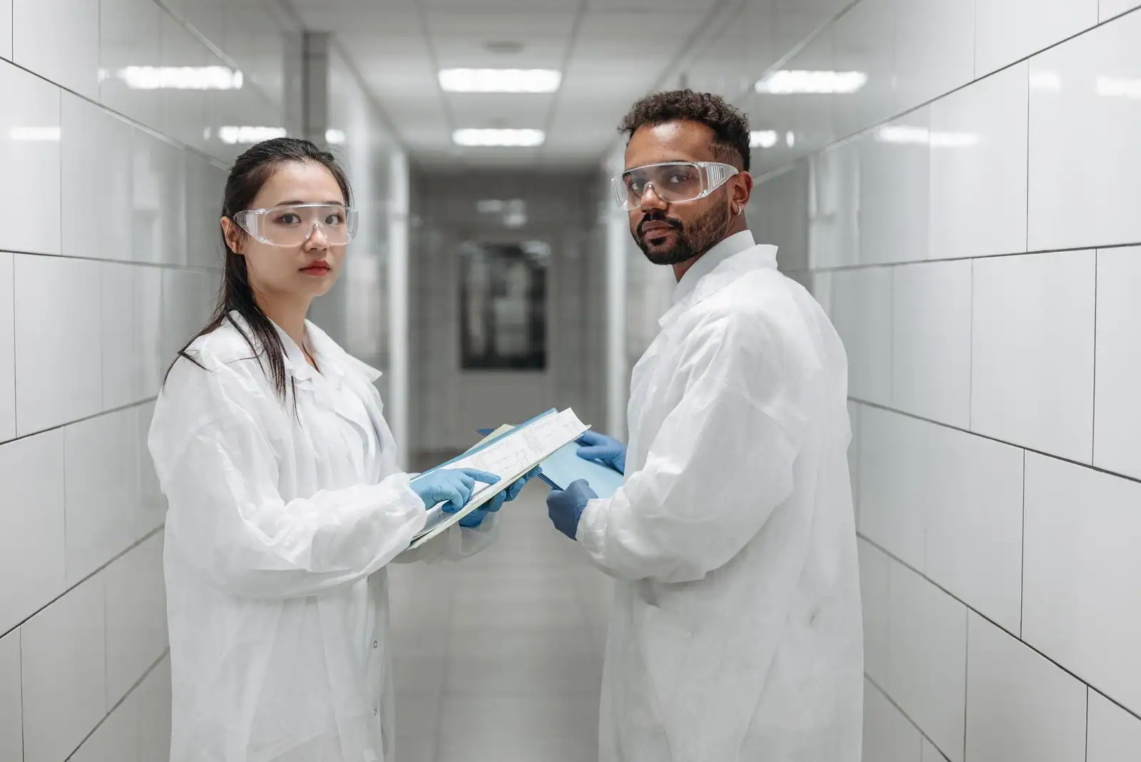Deux chercheurs en blouse et lunettes de protection examinent un document dans un laboratoire de recherche