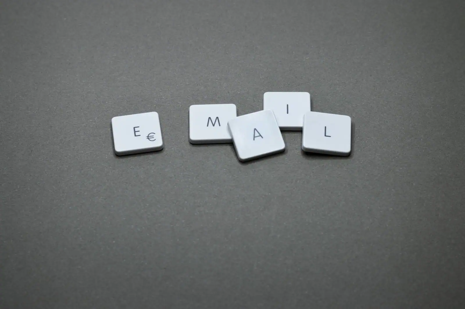 Le mot « email » formé avec des touches de clavier blanches posées sur un fond gris uni