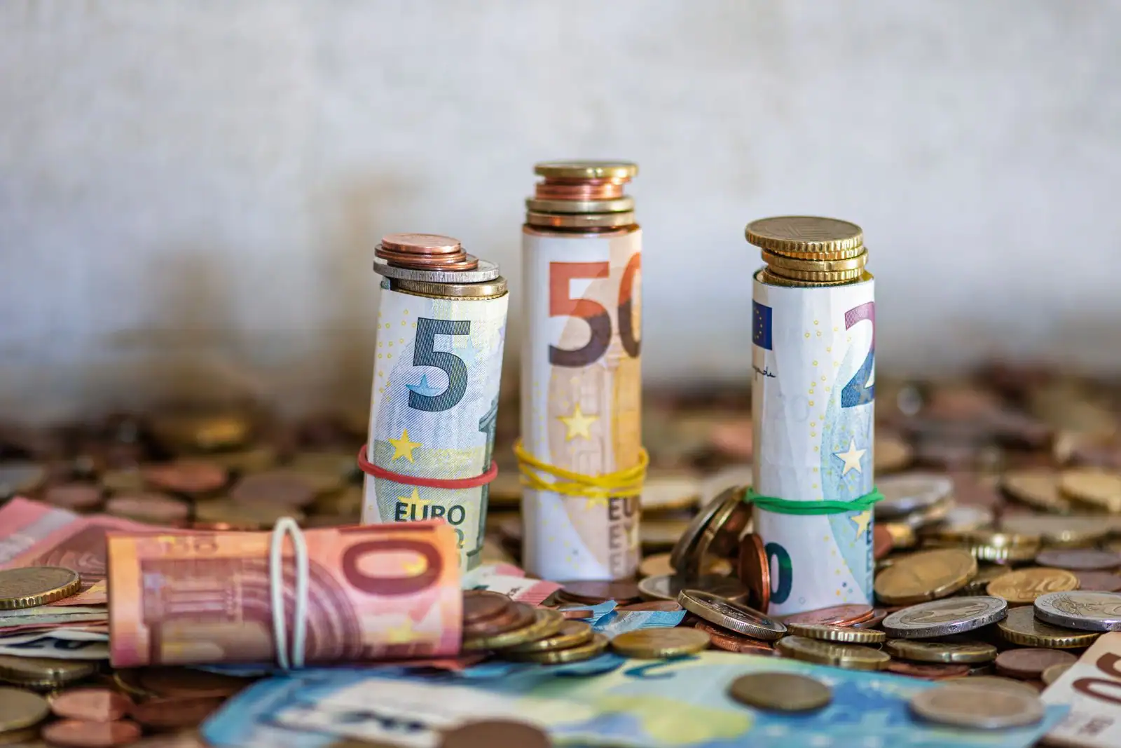 Rouleaux de billets et pièces en euros, illustration de l'épargne salariale à constituer.