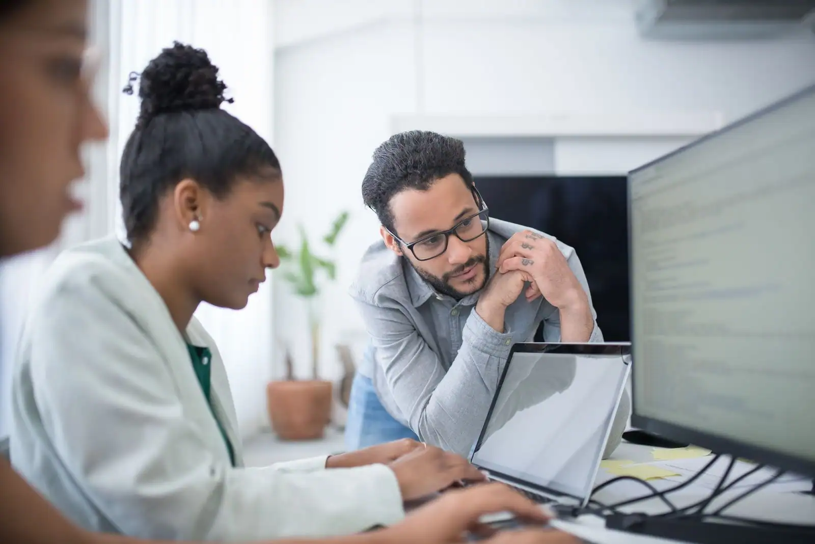 Des collègues réunis autour d'un ordinateur portable, concentrés sur un même écran de travail.