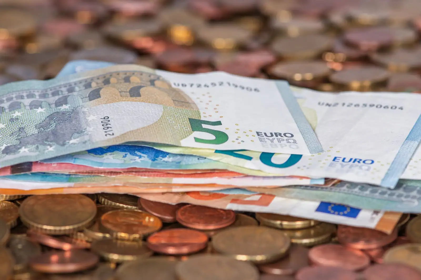 Pile de pièces et de billets en euros symbolisant l'épargne et les produits bancaires réglementés.